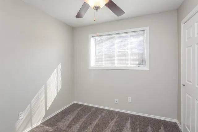 an empty room with a window and a fan