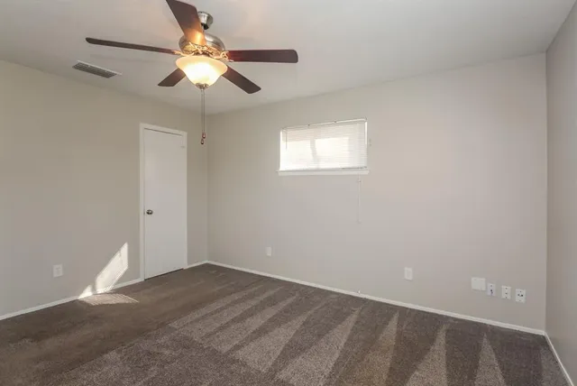 an empty room with a chandelier fan and windows