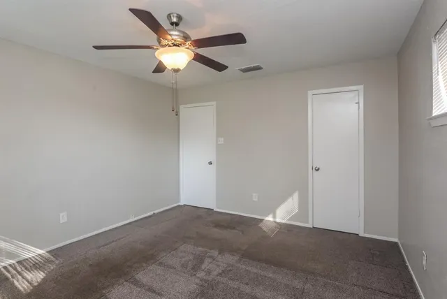 an empty room with a window and a fan