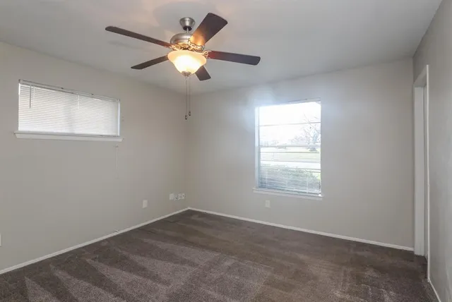 an empty room with a window and a chandelier fan