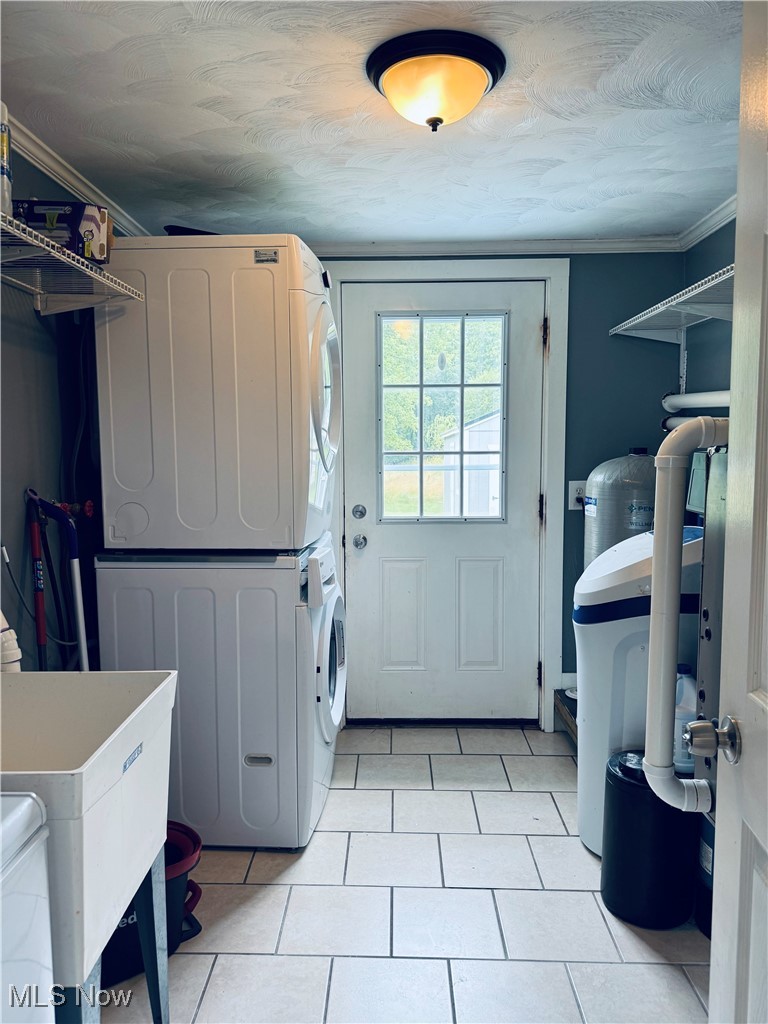 6092 Shaffer Road Northwest Warren, OH 44481 - Photo 21 of 30 Laundry area featuring estacked washer and dryer, light tile patterned flooring, and ornamental molding