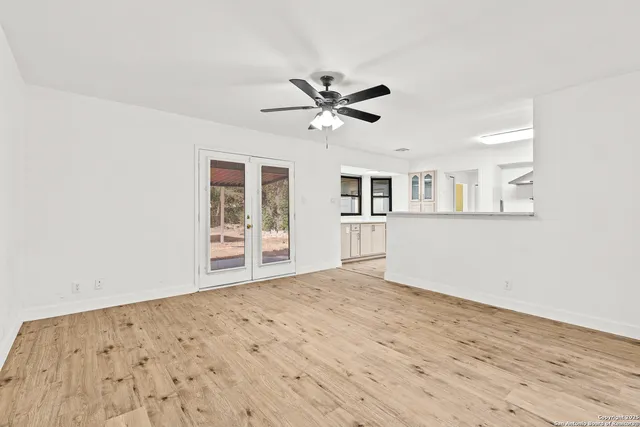 a view of a big room with wooden floor and a chandelier fan
