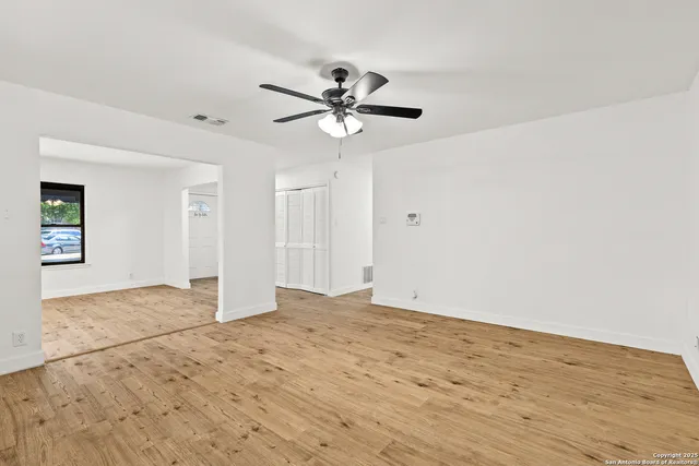 a view of a big room with wooden floor and a chandelier fan