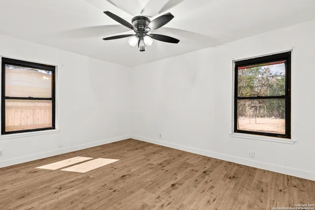 an empty room with wooden floor and windows