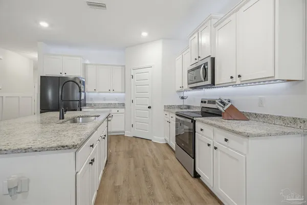 a kitchen with stainless steel appliances granite countertop a sink stove cabinets and wooden floor