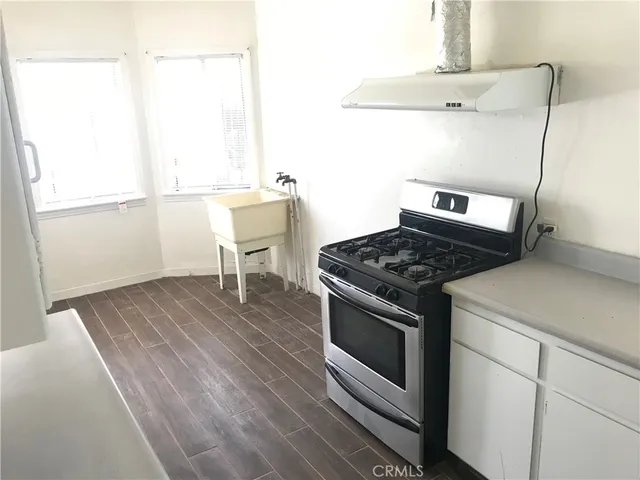 a kitchen with a stove and wooden floor