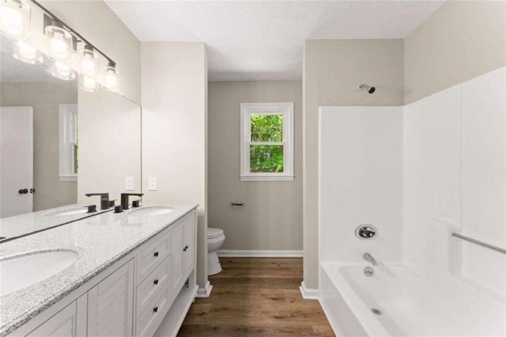 217 Quail Trail Cornelia, GA 30531 - Photo 34 of 48 a bathroom with a double vanity sink a large mirror and a bathtub