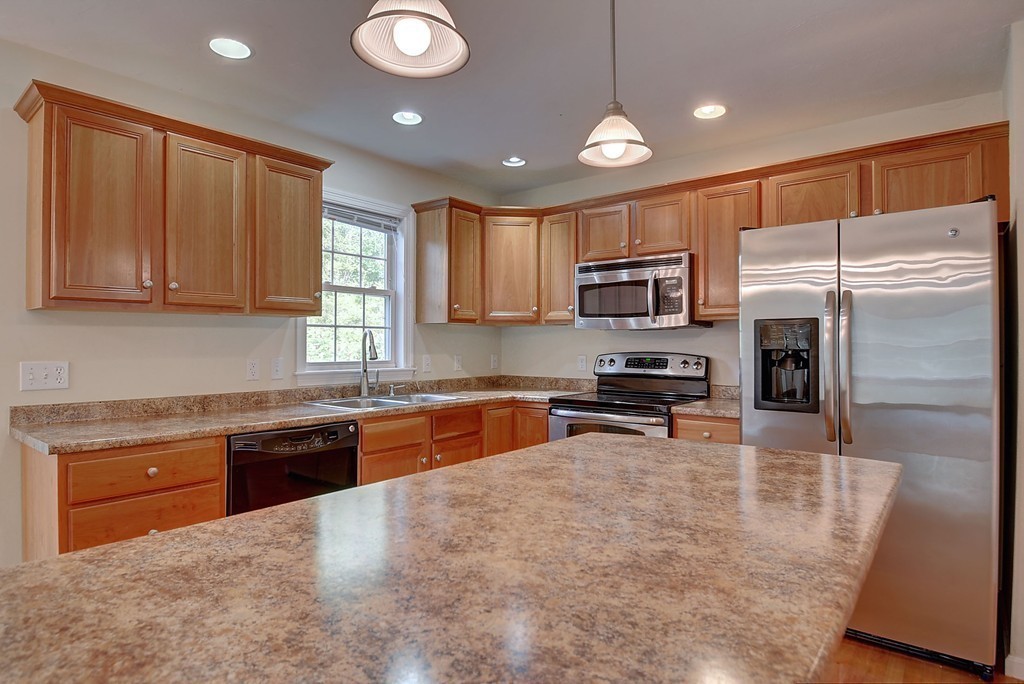 67 Arnold Road Sturbridge, MA 01518 - Photo 7 of 29 a kitchen with granite countertop a refrigerator a sink a stove a microwave a counter top space and cabinets