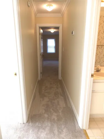 a view of a hallway with wooden floor and a bathroom