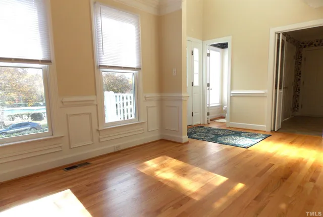 an empty room with wooden floor and windows