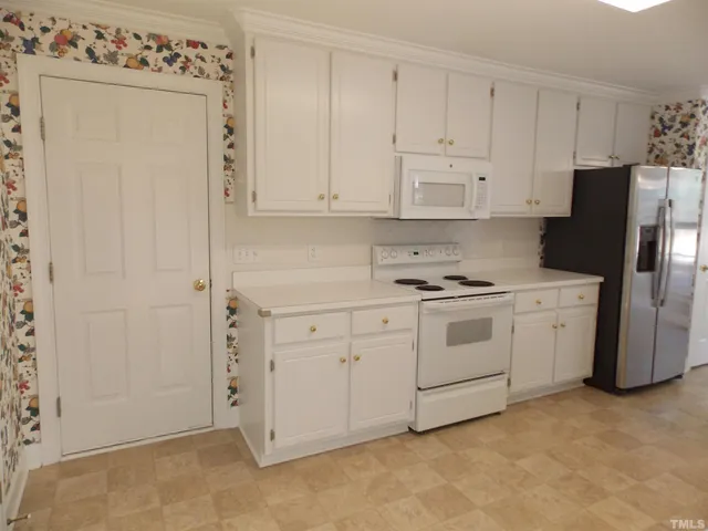 a kitchen with white cabinets and white appliances