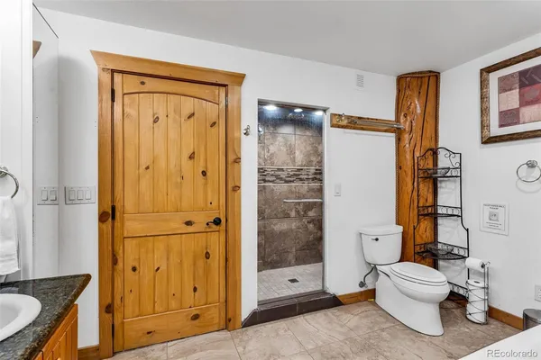a bathroom with a granite countertop toilet a sink and shower