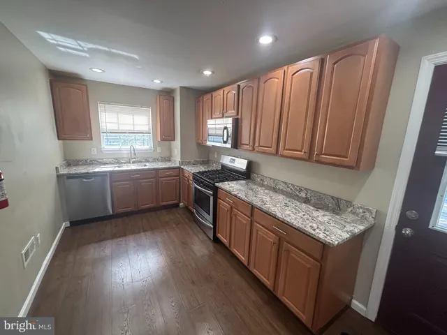 a kitchen with stainless steel appliances granite countertop wooden cabinets a sink a stove a refrigerator and dishwasher