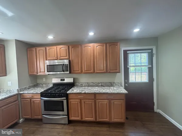 a kitchen with granite countertop kitchen island stainless steel appliances a stove sink and microwave