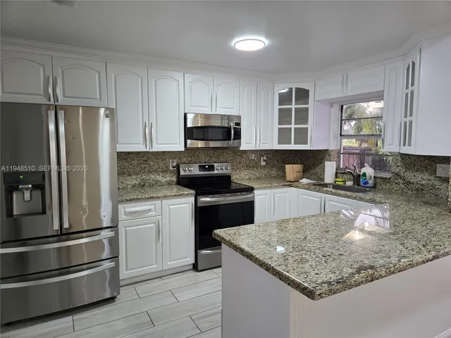 a kitchen with kitchen island granite countertop stainless steel appliances and a counter space