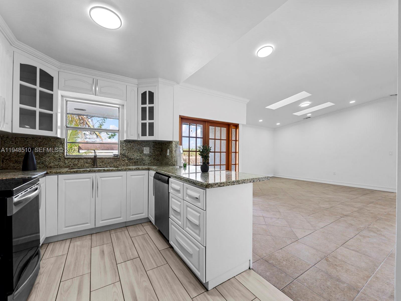 25921 Southwest 130th Avenue Homestead, FL 33032 - Photo 16 of 38 a kitchen with granite countertop a stove a sink and a microwave