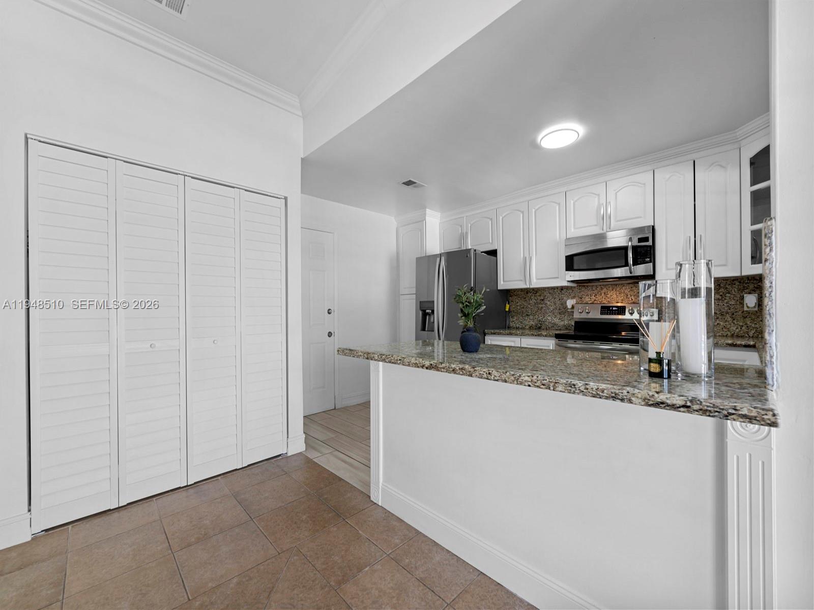25921 Southwest 130th Avenue Homestead, FL 33032 - Photo 29 of 38 a kitchen with stainless steel appliances granite countertop a refrigerator a stove a sink a microwave and white cabinets