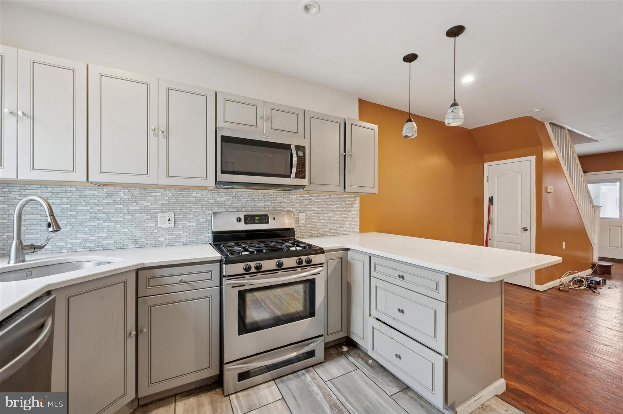 249 West Calvert Street Philadelphia, PA 19120 - Photo 11 of 25 a kitchen with white cabinets stainless steel appliances and wooden floor