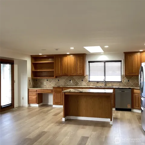 wooden kitchen with stainless steel appliances granite countertop a stove and a sink