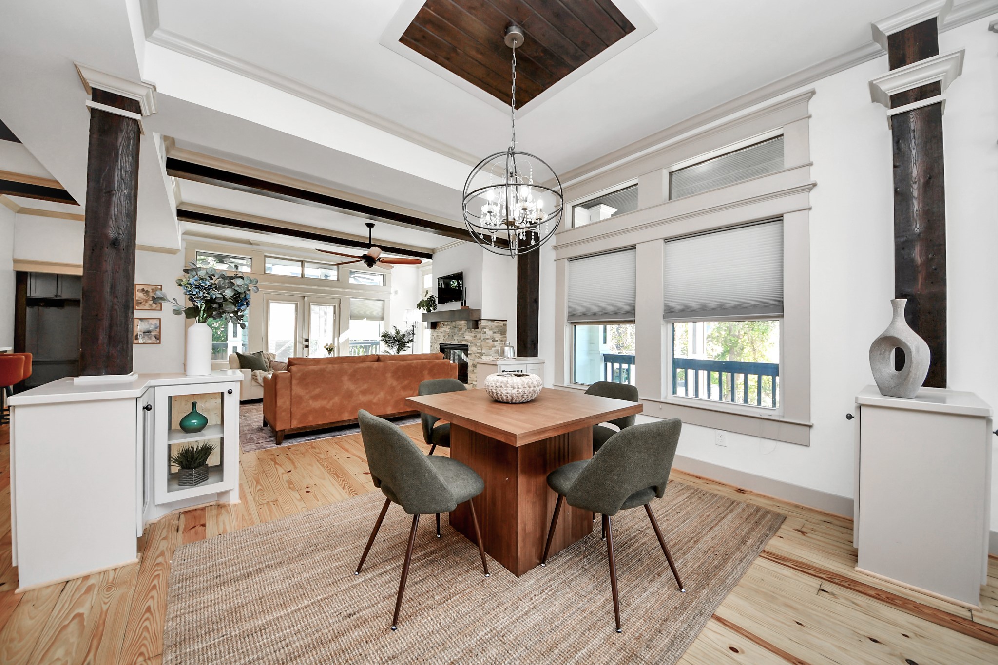 1202 Archer Street Houston, TX 77009 - Photo 22 of 46 This inviting open-concept entry and gathering space features a modern dining area with a stylish chandelier, large windows providing natural light, and a view into a cozy living room with a fireplace. The adjacent kitchen is sleek with contemporary finishes, perfect for entertaining.