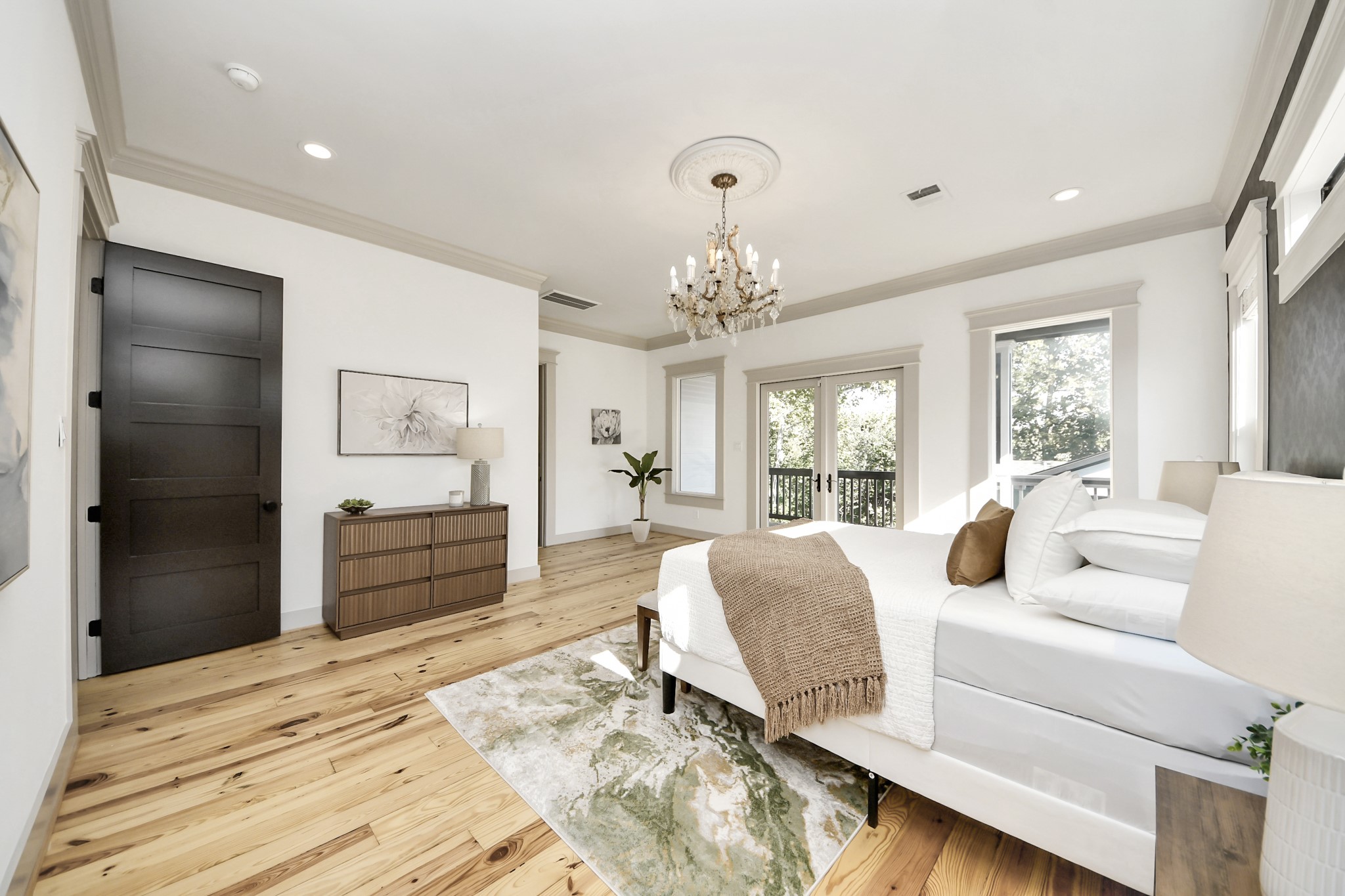 1202 Archer Street Houston, TX 77009 - Photo 25 of 46 This serene and sunlit bedroom features light hardwood floors and crisp white walls, creating a bright and airy atmosphere. The room is adorned with a chic chandelier, modern furnishings, and large windows that fill the space with natural light while offering views of the outdoors, making it a tranquil retreat for rest and relaxation.