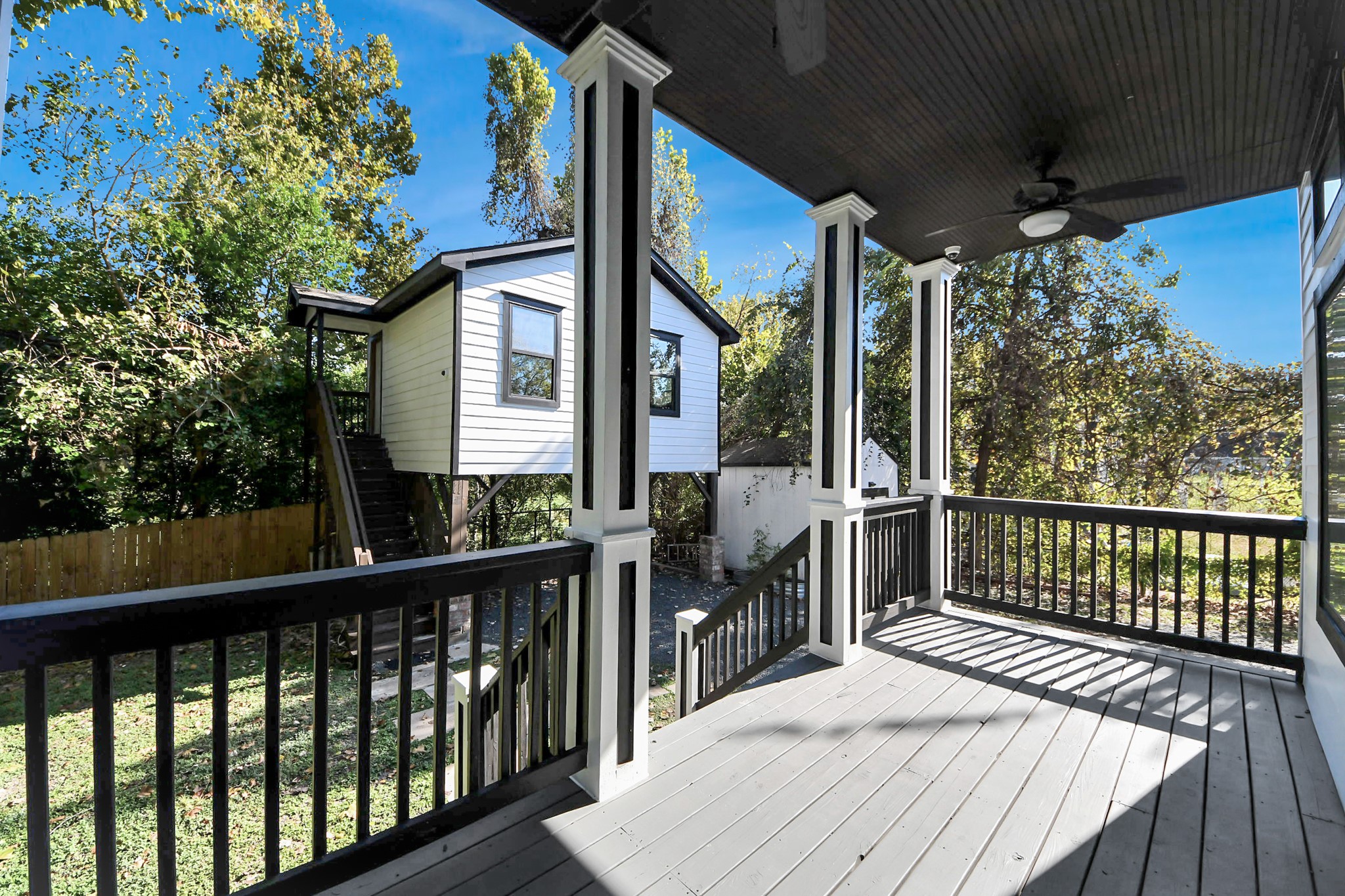 1202 Archer Street Houston, TX 77009 - Photo 10 of 46 This inviting covered porch features elegant railings and a ceiling fan, overlooking a lush, private backyard. A charming detached structure with stairs is nestled among mature trees, creating a serene and cozy outdoor retreat. Elevated tree house offered at 400sqft of living space with staircase access, nestled among trees for
natural privacy. Includes a small shed and gravel driveway, offering practicality and charm.