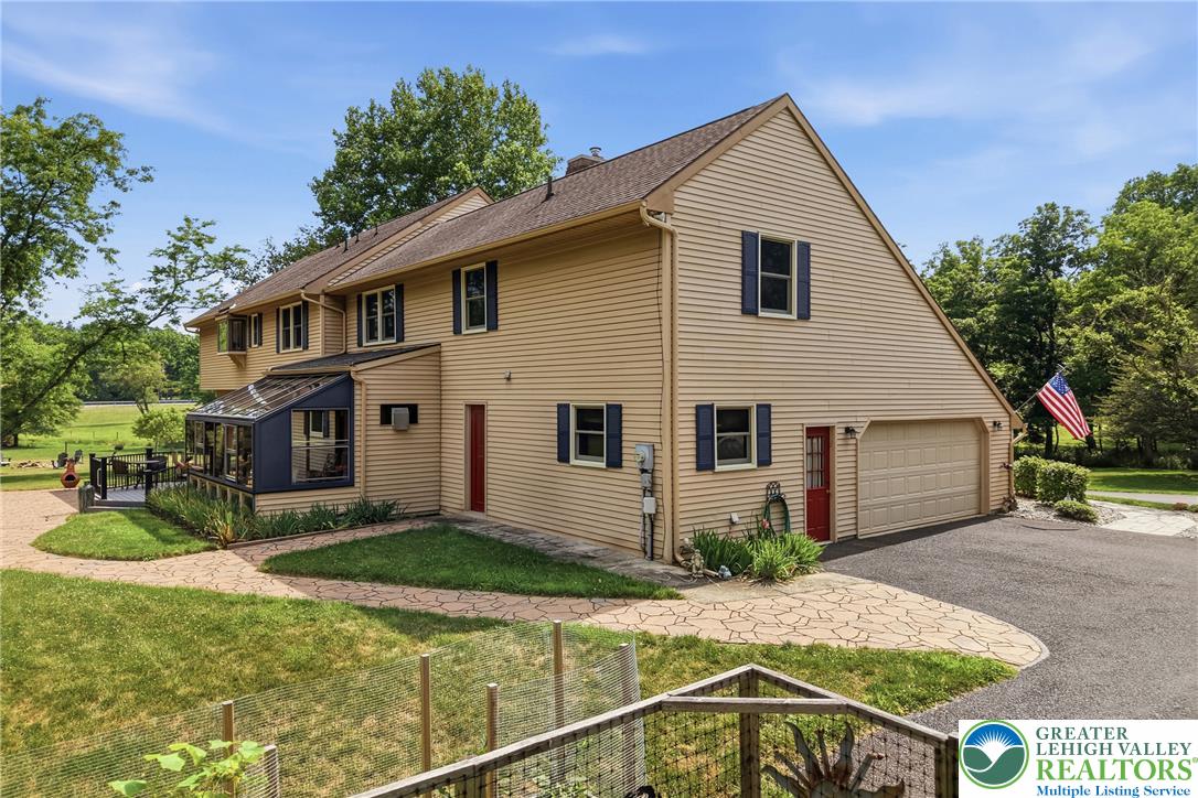 1553 Surrey Road Bethlehem, PA 18015 - Photo 68 of 92 A charming home featuring a sunroom and attached garage, nestled amidst mature trees and a verdant landscape.