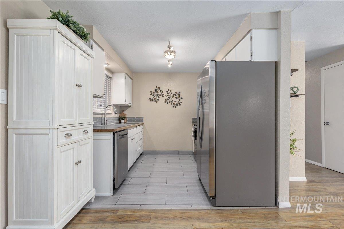 2103 North Hampton Road Boise, ID 83704 - Photo 11 of 40 Kitchen with white cabinets, stainless steel appliances, and light wood finished floors