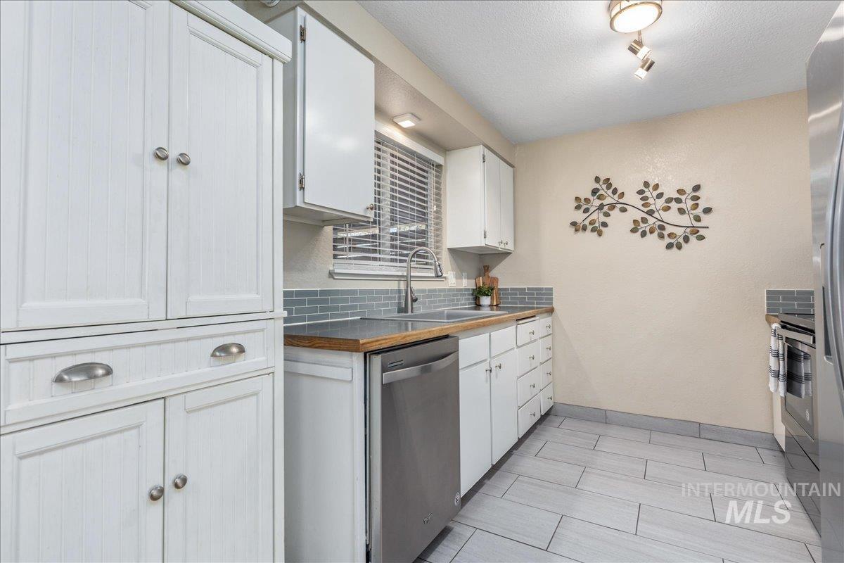 2103 North Hampton Road Boise, ID 83704 - Photo 12 of 40 Kitchen with white cabinetry, stainless steel appliances, butcher block countertops, backsplash, and a textured ceiling