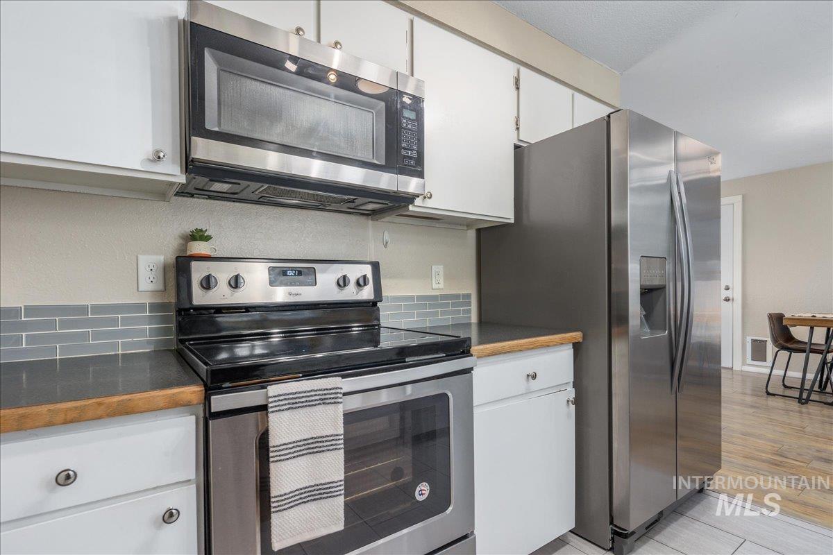 2103 North Hampton Road Boise, ID 83704 - Photo 13 of 40 Kitchen with stainless steel appliances, white cabinets, and dark countertops