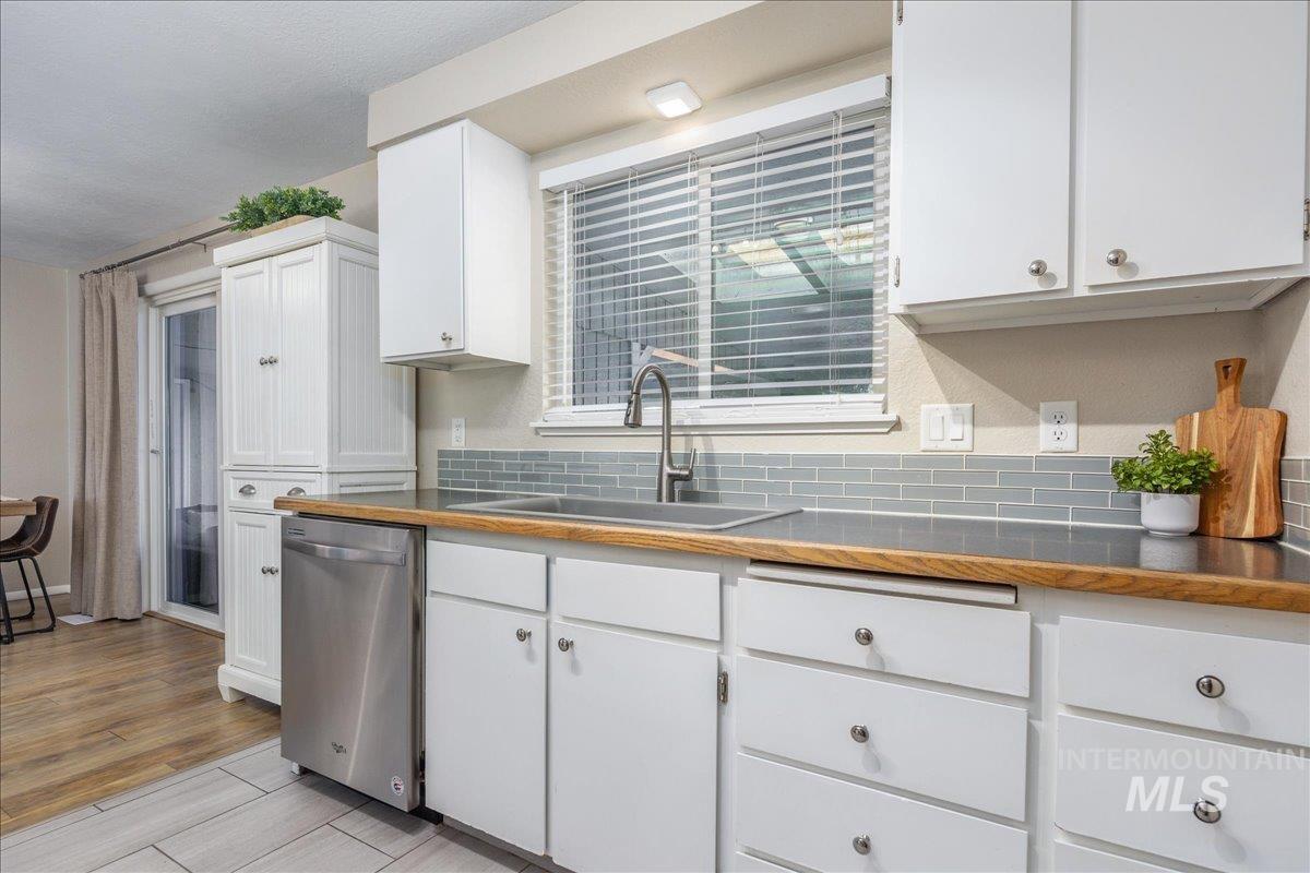 2103 North Hampton Road Boise, ID 83704 - Photo 14 of 40 Kitchen featuring dishwasher, white cabinets, wood finish floors, and decorative backsplash