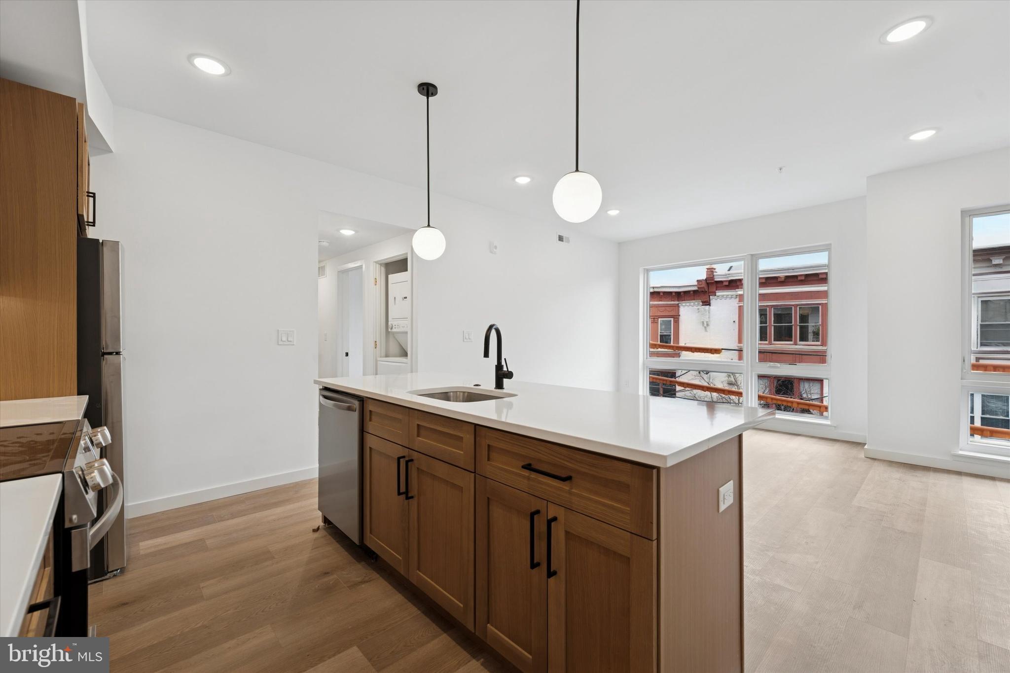 754 South 4th Street, Unit 201 Philadelphia, PA 19147 - Photo 4 of 17 a kitchen with stainless steel appliances granite countertop a sink a oven a dining table and chairs with wooden floor