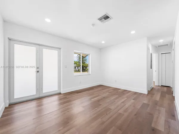 an empty room with wooden floor and windows