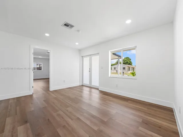 a view of an empty room with wooden floor and a painting