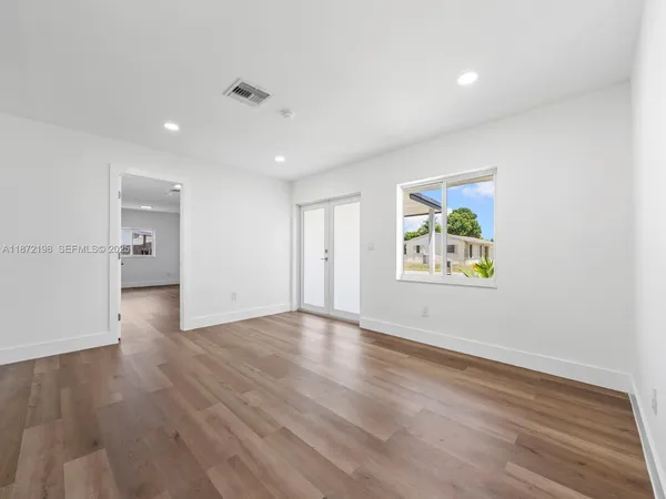 a view of an empty room with wooden floor and a painting