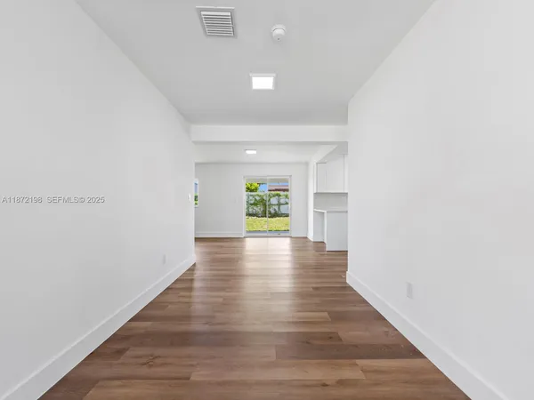 a view of an empty room with wooden floor and a window