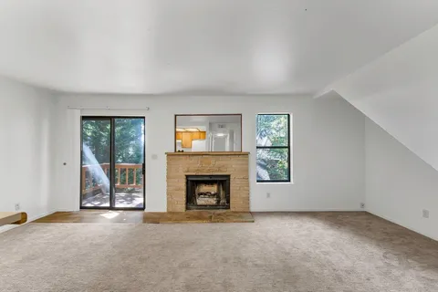 an empty room with windows fireplace and wooden floor