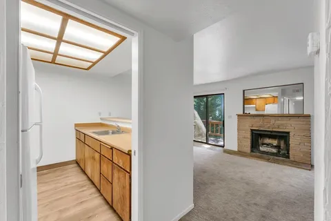 a view of an empty room with fire place and a window