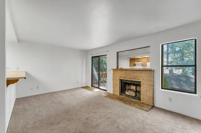 a view of an empty room with a fireplace and a window