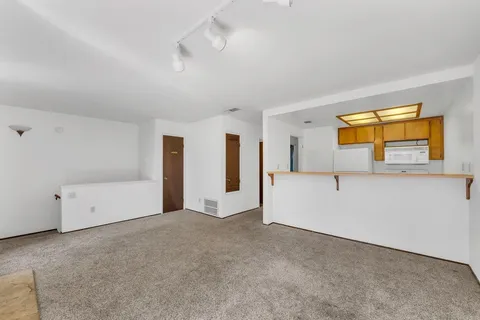 a view of an empty room with window and a livingroom