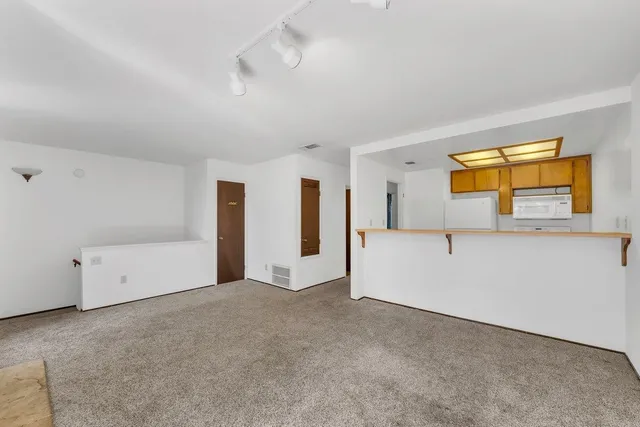 a view of an empty room with window and a livingroom