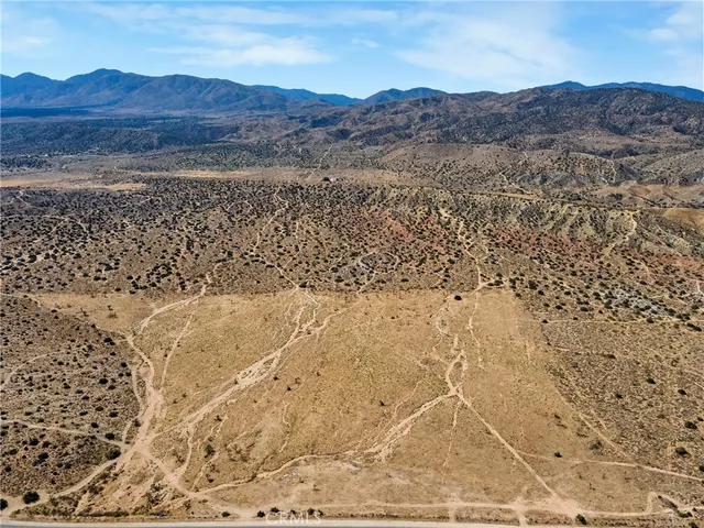 a view of a dry field with mountains in the background