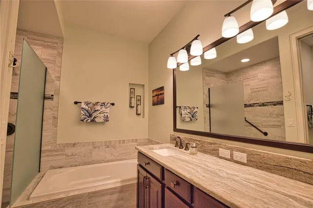 a bathroom with a granite countertop sink a mirror and a bathtub