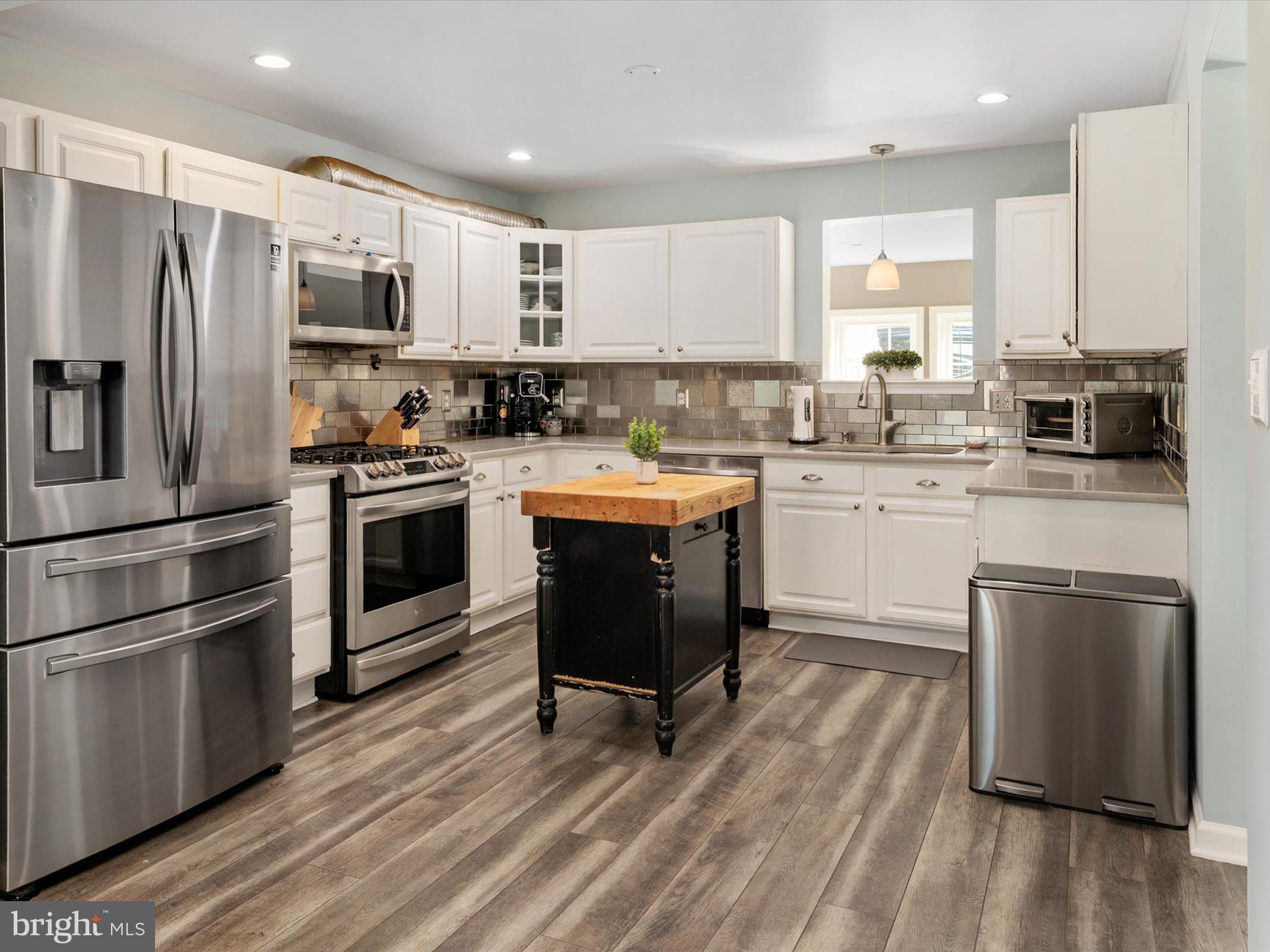 8426 Park Road Pasadena, MD 21122 - Photo 4 of 59 a kitchen with stainless steel appliances a stove a sink dishwasher a refrigerator and a microwave oven with wooden floor