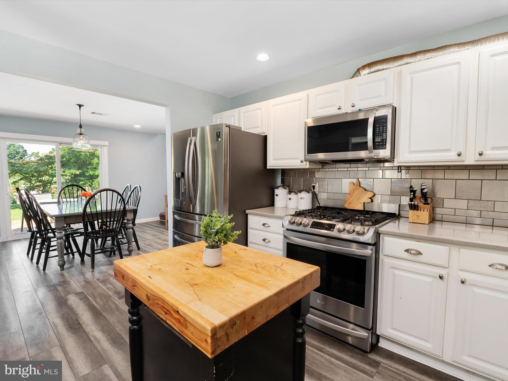 8426 Park Road Pasadena, MD 21122 - Photo 6 of 59 a kitchen with stainless steel appliances granite countertop a stove top oven a sink dishwasher a dining table and chairs with wooden floor
