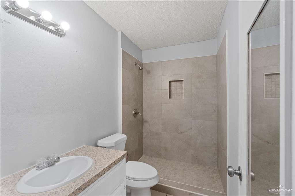 1701 West McIntyre Street, Unit 5 Edinburg, TX 78542 - Photo 14 of 15 Full bath with vanity, a shower stall, and a textured ceiling