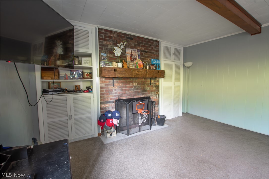 1757 Pleasant Valley Road Northeast New Philadelphia, OH 44663 - Photo 21 of 33 Exposed brick fireplace with a substantial wood mantelpiece, flanked by built-in white cabinetry with louvered doors