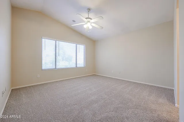 an empty room with windows and ceiling fan