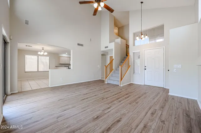 a view of an empty room with wooden floor a ceiling fan and window