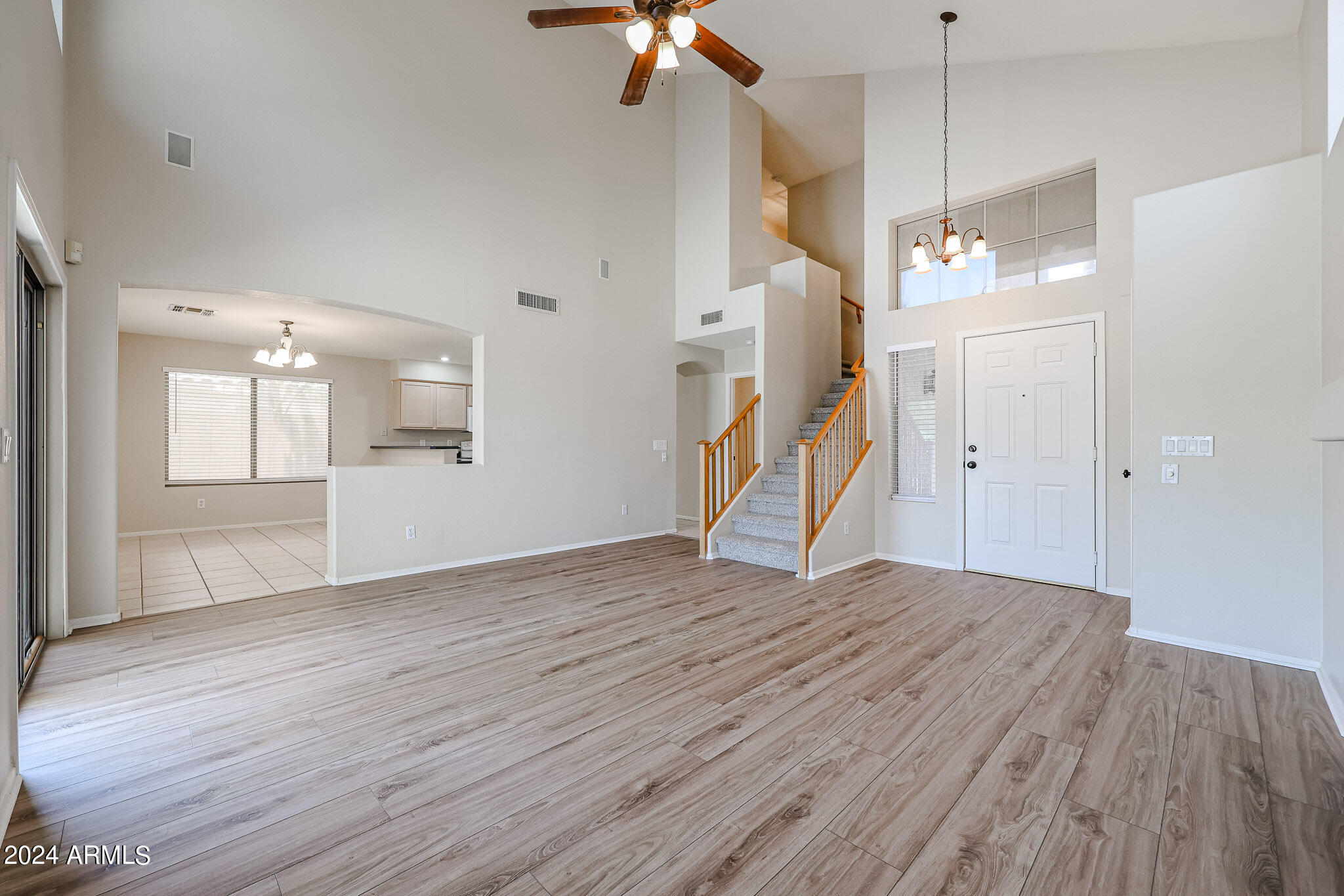 6921 West Juniper Avenue Peoria, AZ 85382 - Photo 4 of 33 a view of an empty room with wooden floor a ceiling fan and window